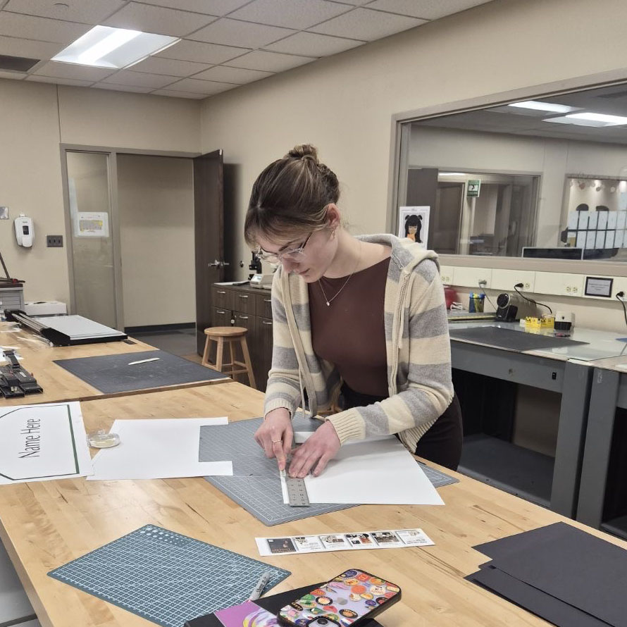 Mattie cutting a piece of paper with an exacto knife.